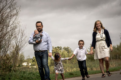 A family of five walking hand-in-hand outdoors, captured by Justin Adelmann, showing a joyful moment of togetherness.